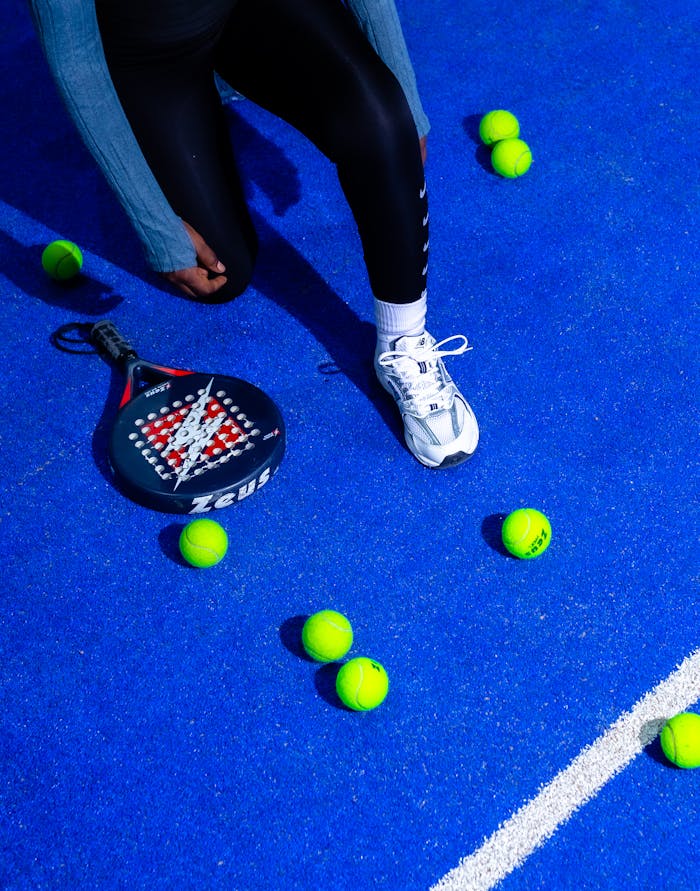 High-energy pádel match on a striking blue court, showcasing racket, balls, and player movement.